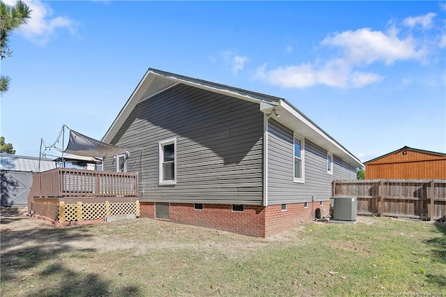 rear view of house featuring fence, central AC unit, a deck, and a lawn