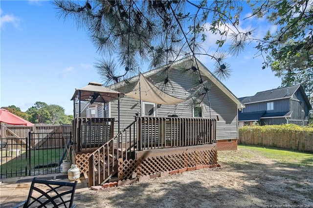 back of property with crawl space, fence, and a deck