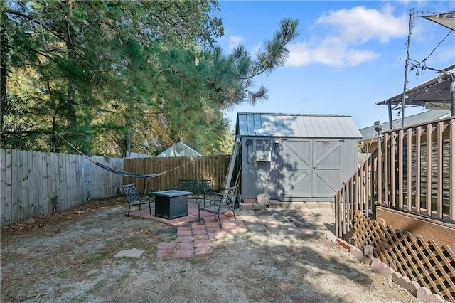 view of yard with a storage shed, an outdoor fire pit, a fenced backyard, an outdoor structure, and a patio area