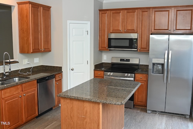 kitchen featuring hardwood / wood-style floors, dark stone counters, sink, a kitchen island, and stainless steel appliances