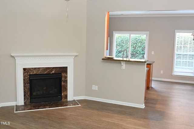 unfurnished living room with a high end fireplace, dark hardwood / wood-style floors, and sink