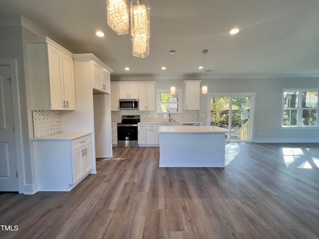 kitchen with a kitchen island, appliances with stainless steel finishes, sink, white cabinets, and hanging light fixtures