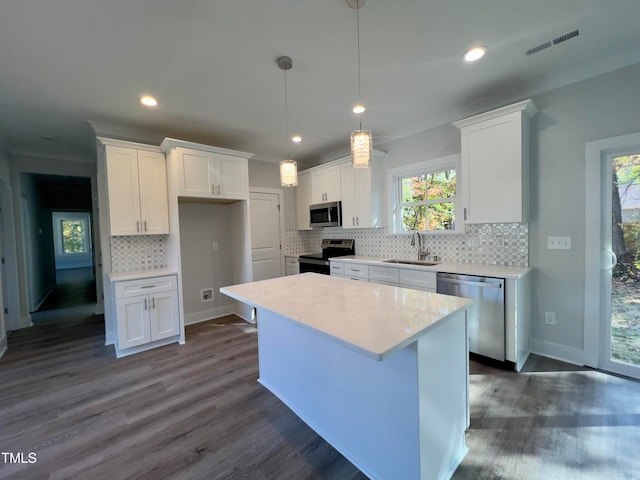 kitchen featuring stainless steel appliances, sink, a kitchen island, and white cabinets