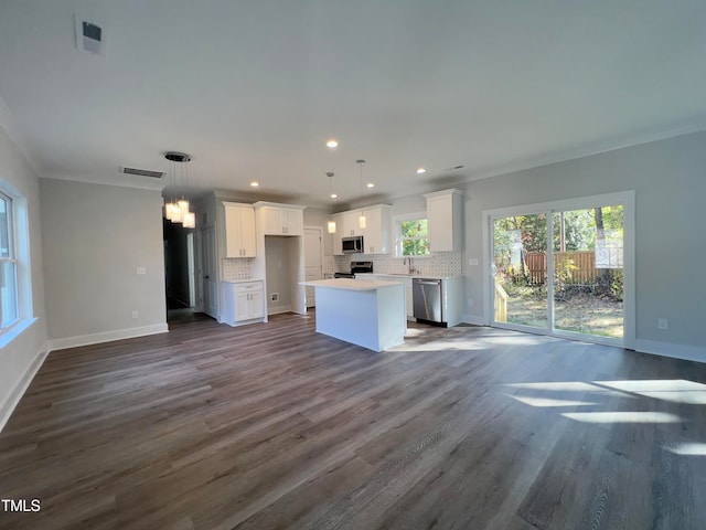 kitchen with decorative light fixtures, white cabinets, decorative backsplash, a center island, and stainless steel appliances