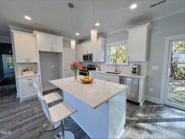 kitchen with a kitchen island, pendant lighting, sink, white cabinets, and stainless steel appliances