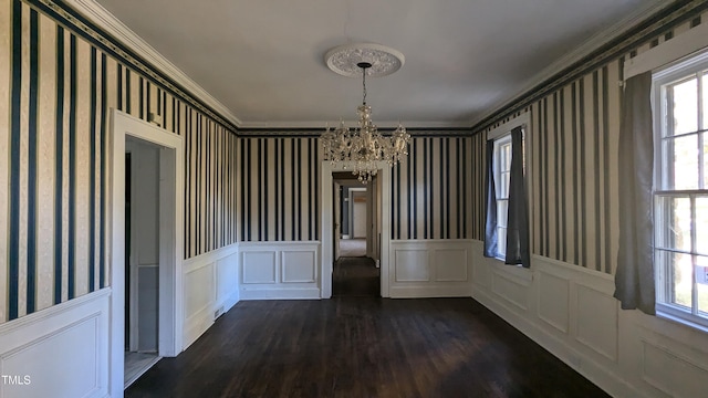 unfurnished dining area with crown molding, dark hardwood / wood-style floors, and an inviting chandelier