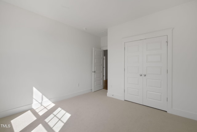 unfurnished bedroom with a closet and light colored carpet