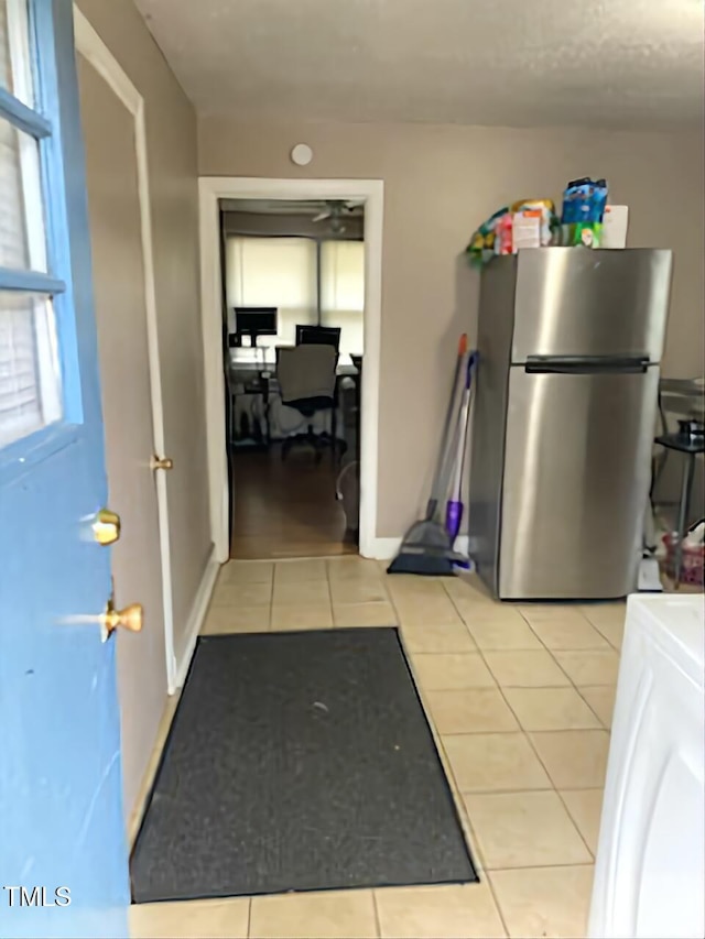 kitchen with freestanding refrigerator, light tile patterned floors, and a desk