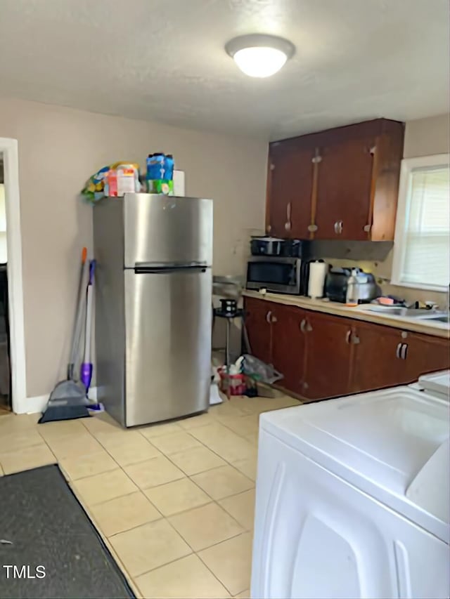 kitchen featuring stainless steel appliances, light tile patterned floors, light countertops, and a sink
