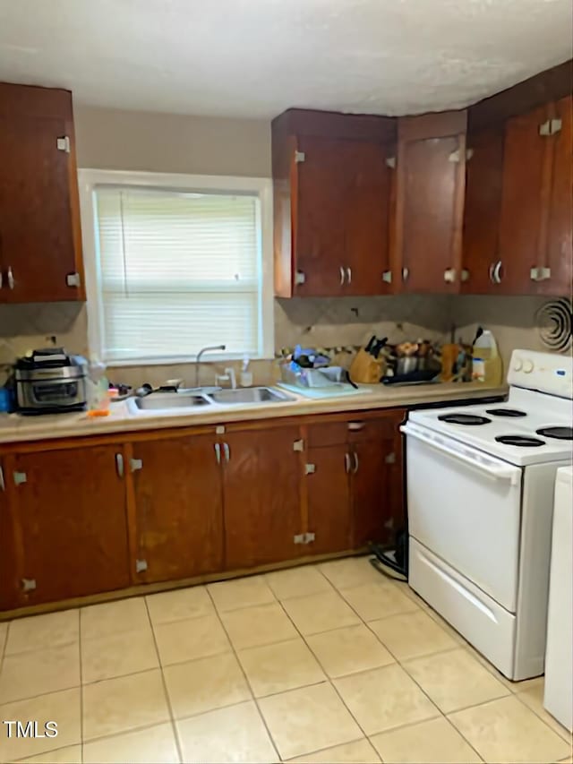 kitchen with light tile patterned floors, sink, and white range with electric cooktop