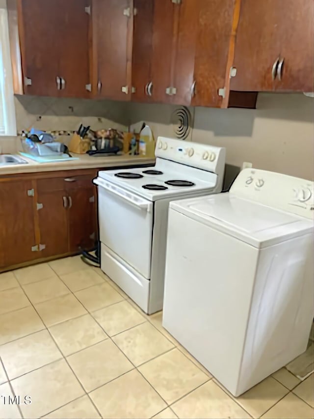 kitchen featuring washer / dryer, electric range, light countertops, and light tile patterned floors