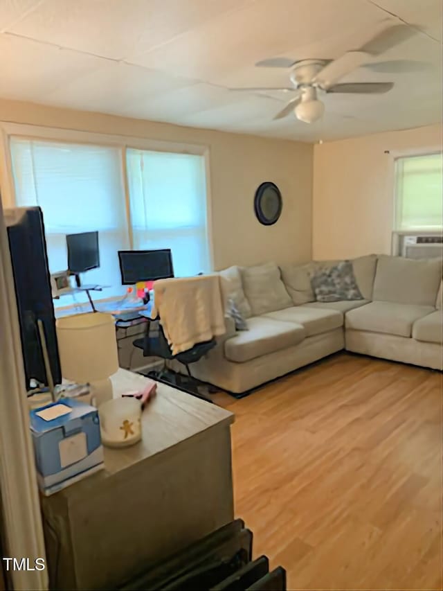 living area with a ceiling fan, healthy amount of natural light, and wood finished floors