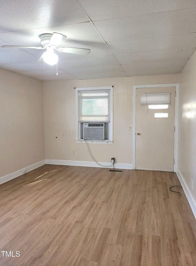 spare room with light hardwood / wood-style floors, cooling unit, ceiling fan, and a paneled ceiling