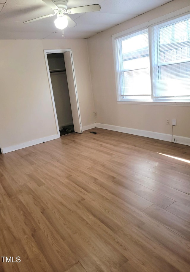 unfurnished bedroom featuring light wood-type flooring, ceiling fan, and a closet