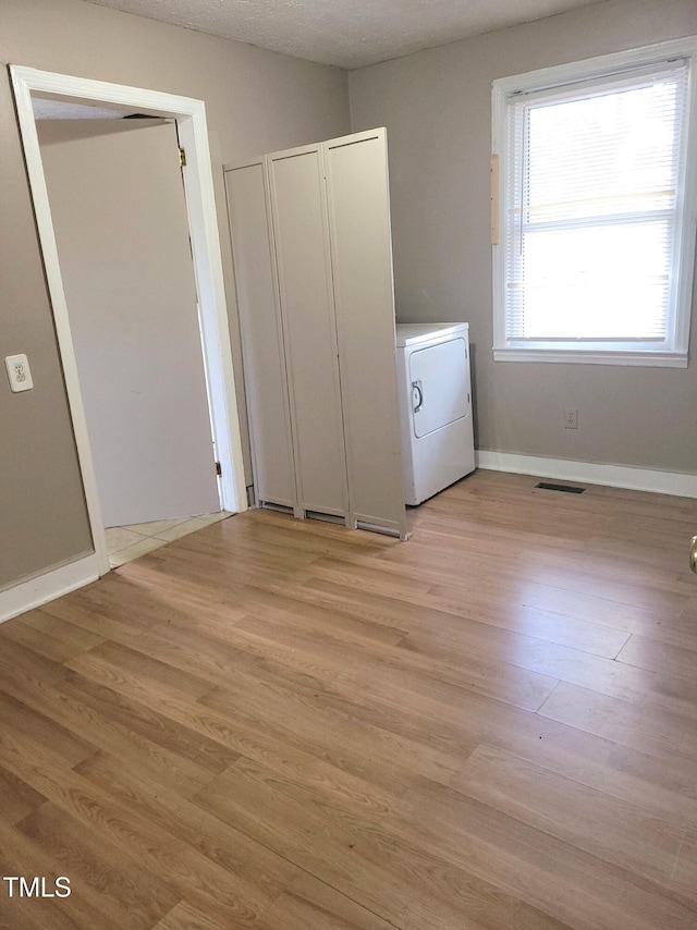 unfurnished bedroom featuring light hardwood / wood-style floors, washer / clothes dryer, and a textured ceiling