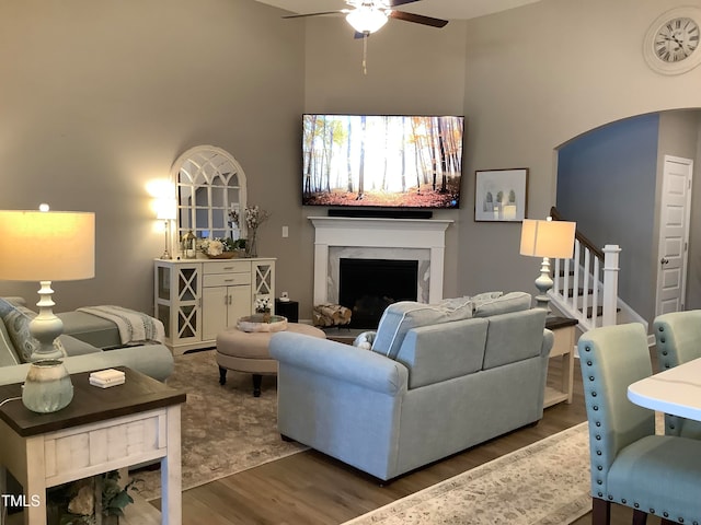 living room featuring a high end fireplace, a high ceiling, dark hardwood / wood-style floors, and ceiling fan