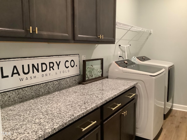 laundry room with washer and dryer, light hardwood / wood-style floors, and cabinets