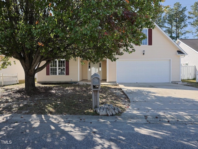 view of property hidden behind natural elements with driveway, a garage, and fence