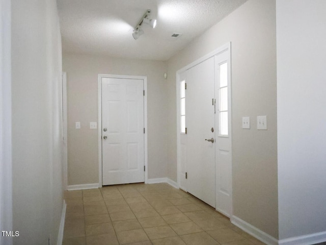 foyer with light tile patterned floors, baseboards, and track lighting