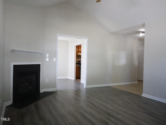unfurnished living room with dark wood-style flooring, a fireplace, vaulted ceiling, and baseboards