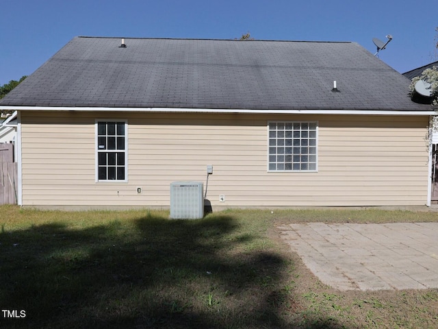 rear view of house featuring central AC unit, a patio area, and a lawn