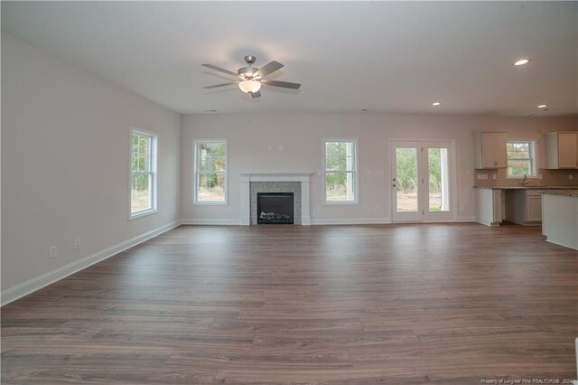 unfurnished living room with ceiling fan, a healthy amount of sunlight, and wood-type flooring