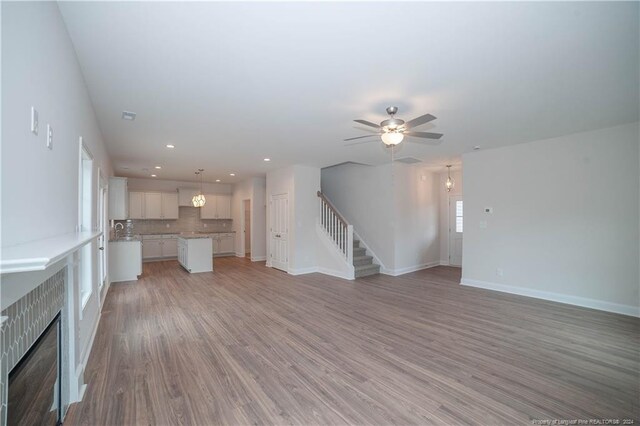 unfurnished living room featuring ceiling fan, light hardwood / wood-style flooring, and sink