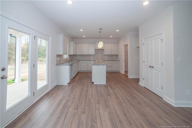 kitchen featuring pendant lighting, white cabinetry, plenty of natural light, and hardwood / wood-style floors