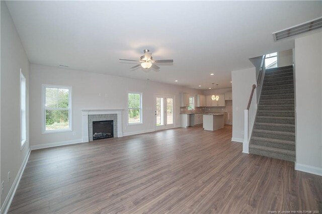 unfurnished living room with ceiling fan, dark wood-type flooring, and a tiled fireplace