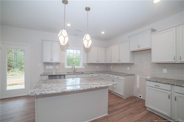 kitchen featuring white cabinets, hardwood / wood-style flooring, a kitchen island, and sink