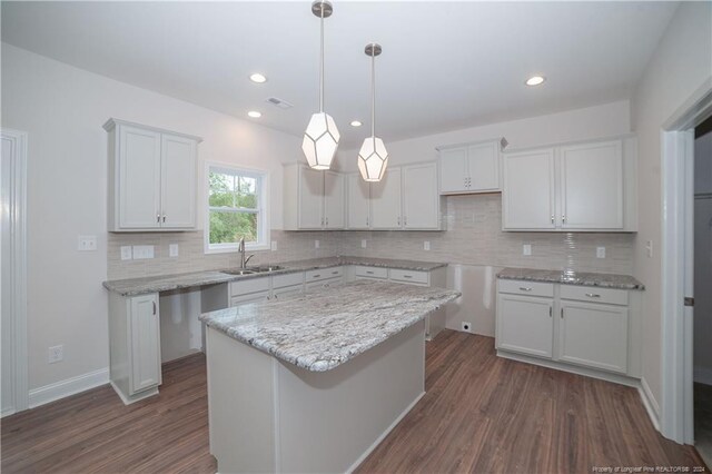 kitchen with a center island, backsplash, white cabinets, sink, and dark hardwood / wood-style flooring