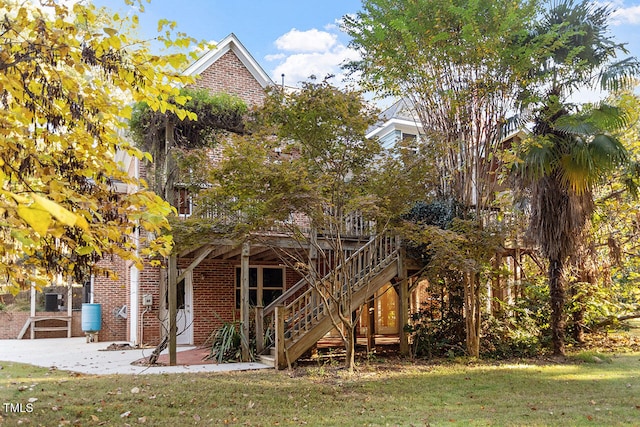 rear view of property featuring a patio area, a wooden deck, and a lawn