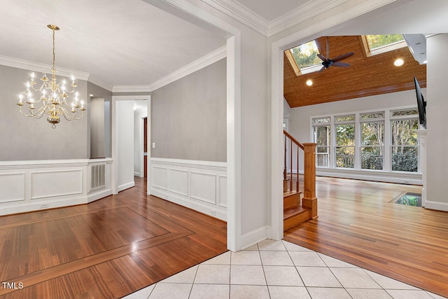 unfurnished dining area featuring a healthy amount of sunlight, ornamental molding, light hardwood / wood-style flooring, and ceiling fan with notable chandelier