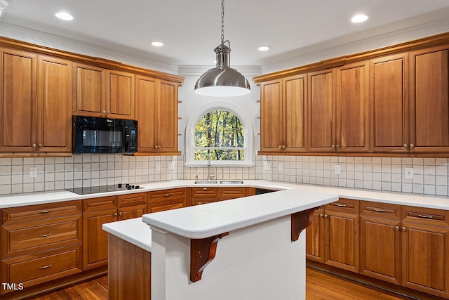 kitchen featuring hanging light fixtures, black appliances, sink, and light wood-type flooring