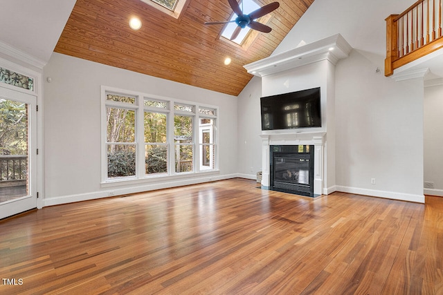 unfurnished living room featuring a wealth of natural light, light hardwood / wood-style flooring, high vaulted ceiling, and a skylight