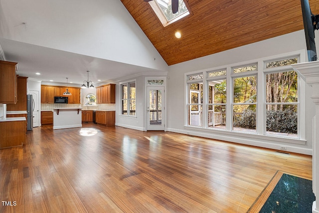 unfurnished living room with wood ceiling, an inviting chandelier, light wood-type flooring, high vaulted ceiling, and a skylight