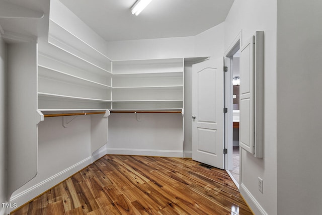 walk in closet with hardwood / wood-style flooring