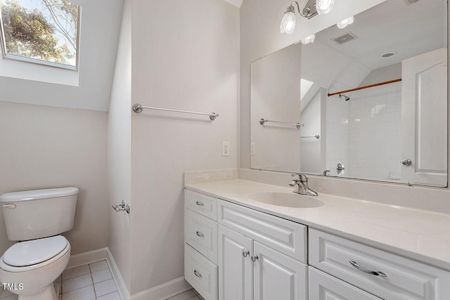 bathroom with toilet, tile patterned floors, vaulted ceiling with skylight, tiled shower, and vanity