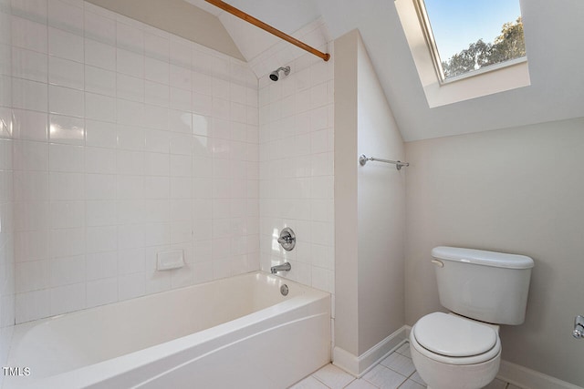 bathroom featuring vaulted ceiling with skylight, tiled shower / bath combo, toilet, and tile patterned flooring