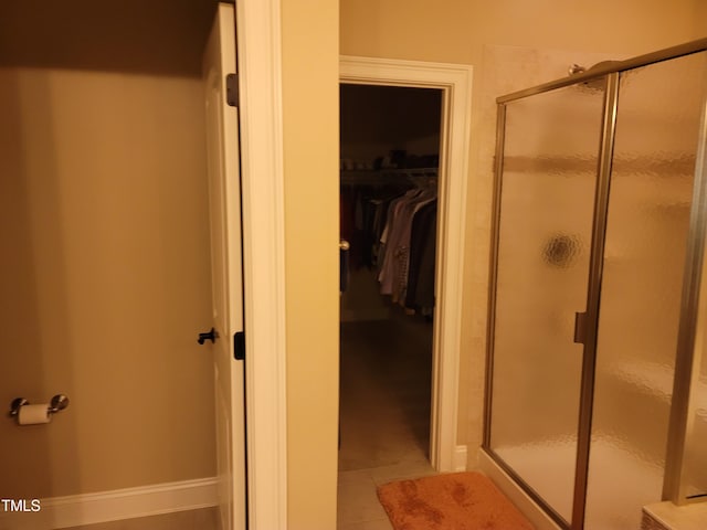 bathroom featuring tile patterned floors, a shower stall, baseboards, and a spacious closet