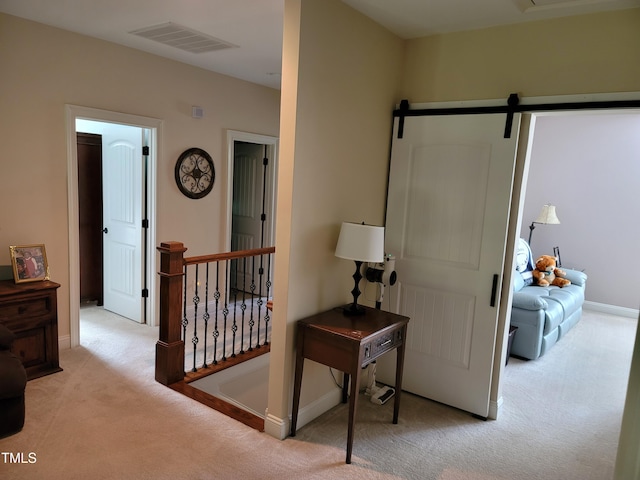 hallway featuring light carpet and a barn door