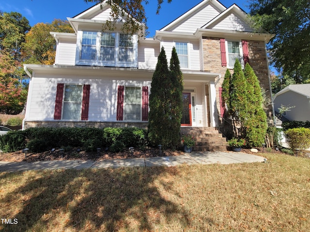 view of front facade with stone siding and a front yard