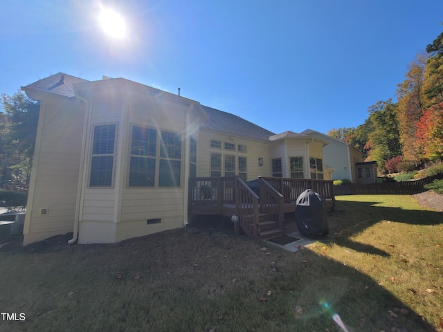 rear view of house featuring a deck and a lawn