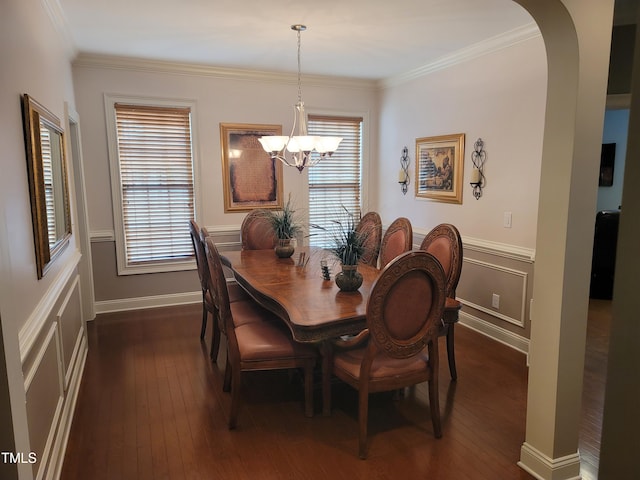 dining space with dark wood-type flooring, crown molding, and a notable chandelier