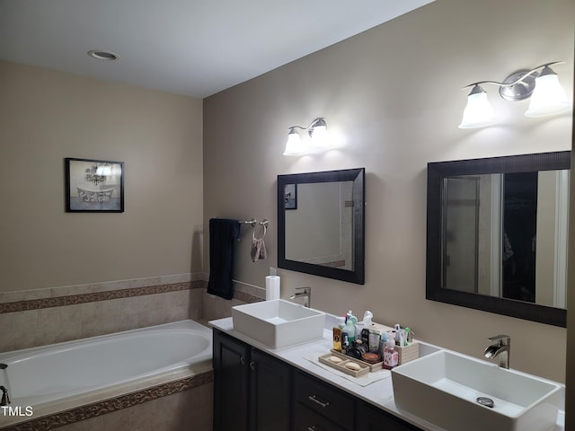 bathroom featuring tiled bath and vanity