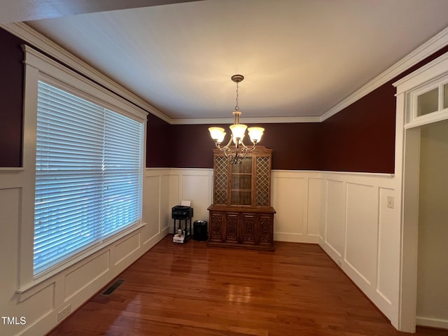 unfurnished dining area featuring crown molding, a notable chandelier, and dark hardwood / wood-style flooring