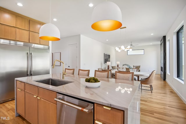 713 N State St, Raleigh, NC 27604 - kitchen featuring stainless steel appliances, open floor plan, light wood-style flooring, a center island with sink, and decorative light fixtures