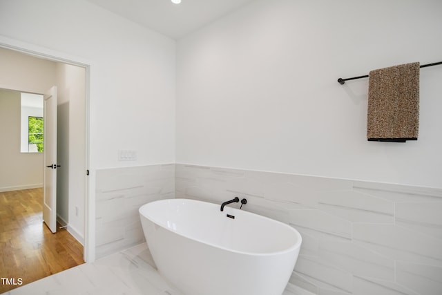 713 N State St, Raleigh, NC 27604 - full bath with a freestanding bath, a wainscoted wall, wood finished floors, and tile walls