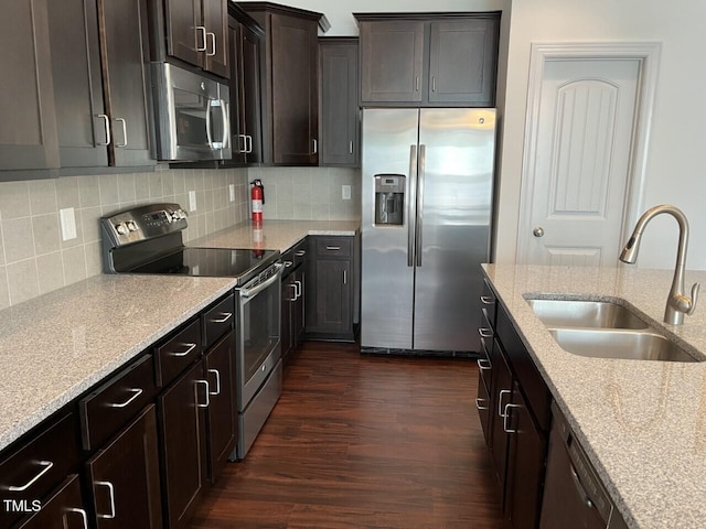 kitchen featuring dark hardwood / wood-style floors, sink, dark brown cabinetry, appliances with stainless steel finishes, and light stone counters