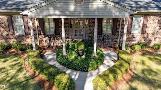 doorway to property with a yard and covered porch